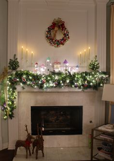 a fireplace decorated for christmas with lights and garland on the mantel above it, surrounded by deer figurines