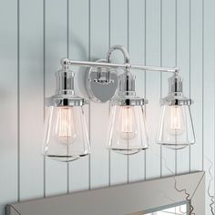 three light bathroom fixture in chrome finish with clear glass shades on the wall and mirror