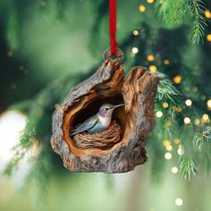 a bird is sitting in a nest hanging from a christmas tree