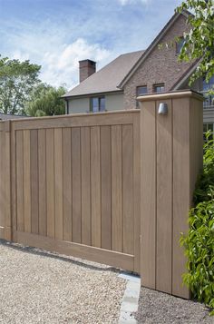 a wooden fence in front of a house with gravel on the ground next to it