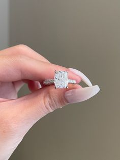 a woman's hand holding an engagement ring with a diamond on the middle and side