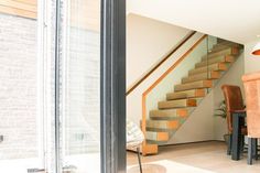 an open door leading to a dining room and kitchen area with stairs in the background