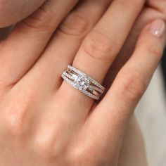 a woman's hand with two wedding bands on her fingers and a diamond ring in the middle