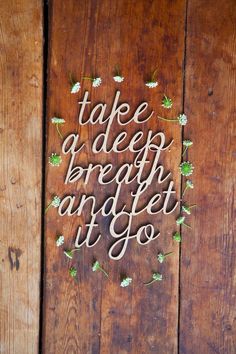 the words take a deep breath and let go are made out of wood planks