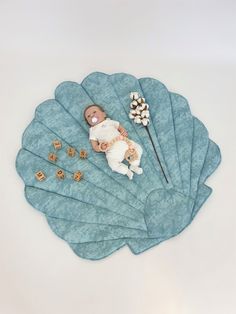 a baby laying on top of a blue leaf next to some dices and a flower