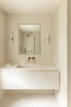 a bathroom with a sink, mirror and light fixture in it's center wall