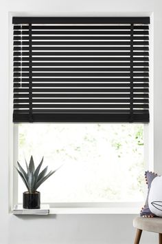 a window with black blinds and a potted plant