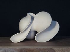 three white vases sitting on top of a wooden table