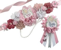 two pink and white hair clips with flowers on them, one has a name tag that says daddy to be