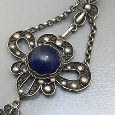 Fine Vintage Art nouveau / Art deco silver filigree pendant necklace ~ Pendant has a central bezel set blue lapis stone set on an filigree base ~ which is attched to a fine filigree chain . Clasp is Marked DRGM / Deutsches Reich Geschmacksmuster for German patent mark . Necklace is acid tested for silver Measurements : Necklace is 20 inches in length x 3/8 inches max chain width .Pendant adds 3 inches in total drop length x 1 1/4 inches max width Weighs 16 grams on my weighing scale . Condition: Traditional Cabochon Round Pendant Jewelry, Traditional Round Pendant Cabochon Jewelry, Traditional Round Cabochon Pendant Jewelry, Traditional Cabochon Jewelry With Round Pendant, Victorian Sterling Silver Filigree Jewelry, Antique Blue Sterling Silver Jewelry, Ornate Cabochon Round Pendant Jewelry, Ornate Medallion Jewelry With Cabochon, Antique Sapphire Filigree Jewelry