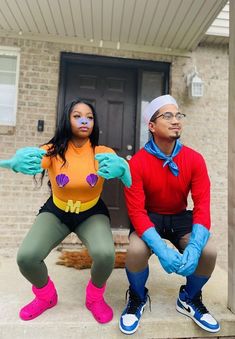 a man and woman dressed up in costumes sitting on the front steps of a house