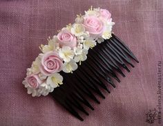 a black comb with pink and white flowers on it sitting on a purple cloth covered surface