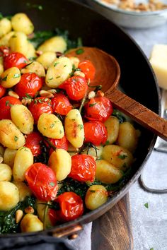 a pan filled with potatoes, tomatoes and spinach