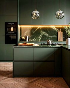 a modern kitchen with green cabinets and marble counter tops, along with hanging lights above the sink