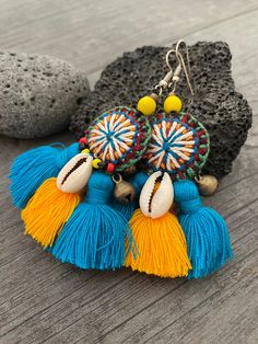 Unique fun and colorful earrings. Made with yellow and blue tassels and a beautiful round center piece made with different fabrics and strings, the earrings are adorned with beads, brass bells and shells. This pair will rock your outfit. Fun and easy to wear as they are super light. The earrings are 6cm- 2.40inch long 5.3cm- 2.10inch wide This timeless pair will brighten up your days! To see more unique and fun colorful tassel earrings, click the link below https://www.etsy.com/shop/AkashiJewelr Yellow Tassel Beach Jewelry, Yellow Tassel Jewelry For The Beach, Yellow Tassel Jewelry For Beach, Yellow Fringe Earrings For Beach, Yellow Bohemian Tassel Earrings For Beach, Colorful Tasseled Jewelry For Gifts, Yellow Tassel Earrings For Festival, Colorful Tassel Jewelry As A Gift, Yellow Tassel Earrings For Beach