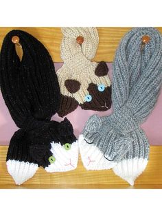 four knitted hats with cats on them sitting on a wooden table next to each other