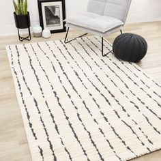 a white rug with black lines on the floor next to a chair and potted plant