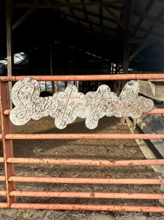 an old metal sign that is on the side of a fence in front of some hay