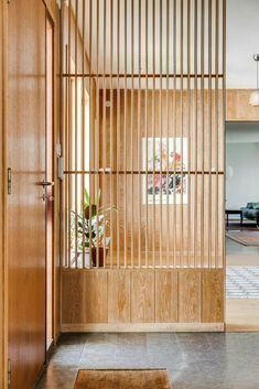 an open door with wooden slats on the wall and potted plants in vases