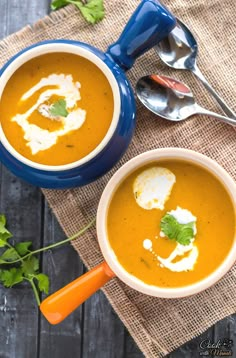 two bowls of soup on a table with spoons