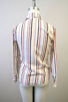 "Description: 1980s white blouse with red, blue, and black stripes. Polyester. Button front with long sleeves. Condition: In great condition, with no holes or stains. Designer: You-nique Stated Size: 7 Measurements: Armpit to armpit: 18\" Shoulder to shoulder: 15\" Sleeve length: 22.75\" Overall length: 25.5\" Waist: up to 31\" ---> If you need an order shipped by a particular date or shipped via a quicker method, please ask PRIOR to purchase to see if we can accommodate that request. Visit t Multicolor Long Sleeve Top With Vertical Stripes, Fitted Button-up Tops With Vertical Stripes, Fitted Vertical Stripe Button-up Tops, Fitted Button-up Blouse With Vertical Stripes, Fitted Vertical Stripes Button-up Blouse, Retro Workwear Tops With Striped Collar, Retro Tops With Striped Collar For Work, Retro Striped Fitted Blouse, Retro Fitted Striped Blouse