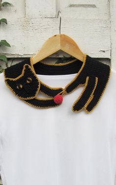 a white shirt with a black cat on it and a red rose in the collar