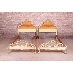 a pair of twin size beds sitting next to each other in front of a brick wall