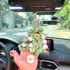 a person's hand hanging from the dashboard of a car with flowers on it