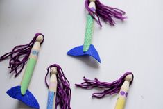 three mermaid toothbrushes with purple and green hair are on a white surface next to each other