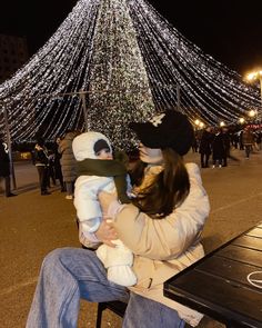 a man and woman sitting on a bench with a baby in front of a christmas tree