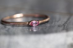 "A dainty marquise pink sapphire is at the center of our \"Wink\" ring, giving you just a little wink of sparkle! - Marquise stone measures 4mm x 2mm - Handcrafted out of 14K yellow, rose, or white gold - Round band measures 1.2mm in width Processing Times - Current processing time is 1 - 3 weeks. Each Item is handmade to order with love and care! In Stock Items - Contact Liesel Love with any rush order questions, or to see if we have anything ready made and in stock. Returns - Liesel Love does Pink Marquise Jewelry For Anniversary, Pink Marquise Cut Promise Ring, Pink Marquise Cut Ruby Ring For Anniversary, Pink Gemstone Birthstone Ring With Open Shape, Pink Marquise Promise Ring, Marquise Pink Rings With Accent Stones, Pink Marquise Cut Jewelry As Gift, Pink Marquise Rings For Gifts, Pink Marquise Ruby Ring