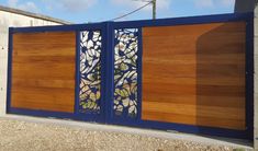 a wooden gate with stained glass panels on the top and bottom part, in front of a house