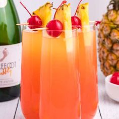 two glasses filled with orange juice and pineapple garnish