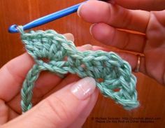 someone is crocheting the end of a piece of green yarn with a blue needle