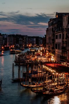 a river filled with lots of boats next to tall buildings and lights on the water