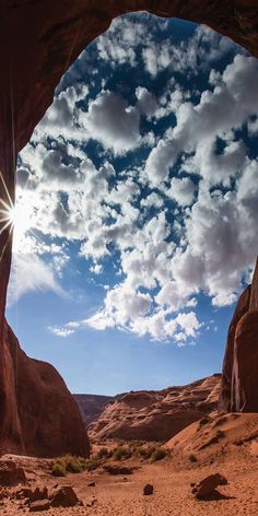 the sun is shining through an arch in the desert