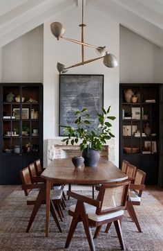 a dining room table with chairs and a potted plant on top of the table