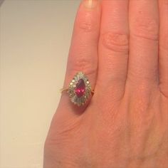 Here we have a gorgeous vivid red natural ruby and diamond ballerina style engagement ring dating to the mid century era. At the heart of this gorgeous ring sits a 1.30 carat marquise cut natural earth mined ruby. This large ruby measures approximately 9.50mm x 5.22mm x 3.60mm. Surrounding this exceptional gem quality ruby there is a halo of diamond accents set into a ballerina tiered setting. There are ten baguettes and eighteen round brilliant cut diamonds all VS clarity and G/H/I in color. Th Red Baguette Cut Diamond Accent Rings, Baguette Cut Ruby Ring For Anniversary, Red Ruby Ring With Brilliant Pear-shaped Cut, Red Pear-shaped Ruby Ring With Brilliant Cut, Fine Jewelry 14k Gold Pear-shaped Ruby Ring, Fine Jewelry Pear-shaped Ruby Ring With Diamond, 14k Gold Pear-shaped Ruby Ring, Pear-shaped Ruby Rings With Rose Cut Diamonds, 14k Gold Pear-shaped Ruby Ring For Wedding