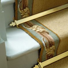 a carpeted stair case with two gold rails on the top and bottom of it