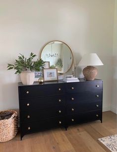 a black dresser with a mirror and potted plant on it in a living room