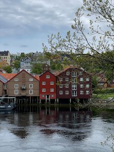 a boat is in the water next to some red buildings and trees with no leaves on them