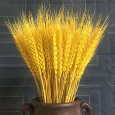 a brown vase filled with yellow stalks of wheat