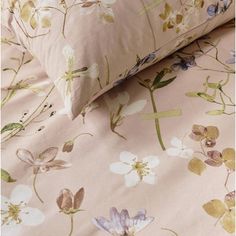 a bed with pink and yellow flowers on the comforter next to pillowcases