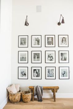 a wall with many pictures on it and some baskets under the bench next to it