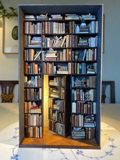 an open bookcase with many books on the shelves in front of it, sitting on top of a table