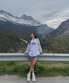 a woman is sitting on a bench looking up at the mountains and snow capped peaks