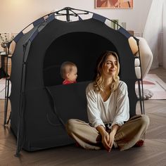 a woman sitting on the floor next to a child in a small black podoo