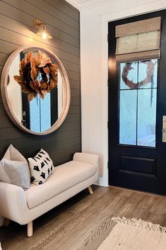 a white couch sitting in front of a door next to a table with a mirror on it