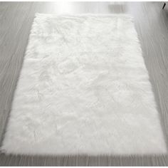 a large white rug on top of a wooden floor