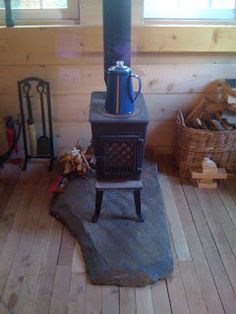 a wood stove sitting on top of a wooden floor next to a pile of logs